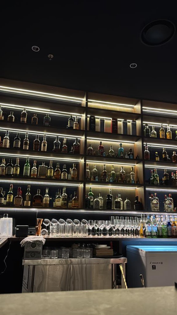 Backlit spirits wall behind the bar at Tipsy Plus One